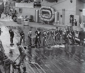 Black-and-white photograph of sailors scrubbing a ship's deck