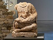 Statue of Cernunnos from Verteuil, Charente. The figure holds a small stag, a torc, and a bag of coins; its head has been purposefully removed.