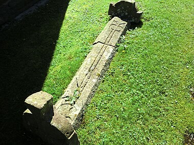 Förromanskt gravmonument, med lockhäll och två gavelhällar, på kyrkogården.