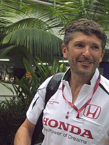 Photo de Nick Fry, souriant en chemise Honda et portant un sac à dos