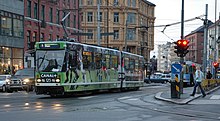 A tram with advertisements at a busy intersection