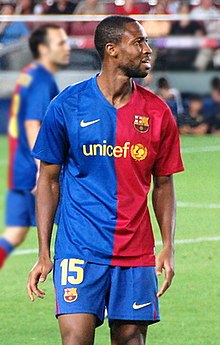 Photographie d'un joueur avec le maillot bleu et rouge de Barcelone, en train de regarder une tribune