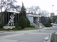 External view of the museum clad in steel and glass with a statue depicting as in-game football catch and tackle