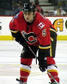 Hockey player in red Calgary Flames jersey standing in a hunched position