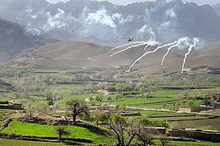 An AH-64 Apache helicopter shoots flares over a valley in Daykundi Province