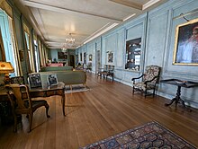 A long, narrow room displaying a range of oil painting, ceramics and antique furniture