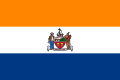 A flag with three equal horizontal stripes colored orange, white, and blue from top to bottom. In the center is the city seal (except for text and circular outline).