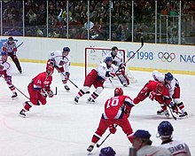 Un match de hockey sur glace entre une équipe habillée en blanc et une équipe habillée en rouge.