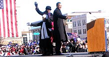 Obama stands on stage with his family. They wave.