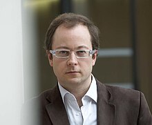 Un homme regarde fixement l'objectif à travers ses lunettes