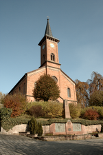 Die ev. Kirche, Frontansicht mit Kriegerdenkmal davor