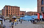 Red-brick buildings with orangey-pink support arches for covered walkways around a square dock.