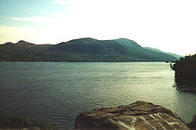 Un lac calme et des collines en arrière-plan.