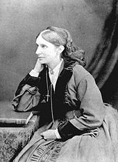 Das Schwarz-Weiß-Foto zeigt Josephine Butler mit fast fünfzig Jahren. Sie ist im Halbprofil zu sehen, da sie links aus dem Bild schaut. Sie sitzt leicht zum Tisch rechts neben ihr gebeugt und hat den rechten Ellbogen auf den Tisch gestützt, ihre rechte Hand fasst an ihre rechte, nicht sichtbare Gesichtshälfte. Der andere Arm liegt in ihrem Schoß. Ihre Haare sind gescheitelt und hinten zusammengefasst, vermutlich in einem Dutt. Auf dem hinteren Oberkopf ist eine flache Kopfbedeckung befestigt, von dem ein Tuch oder Schleier bis zur Schulter herabfällt. Sie trägt ein Kleid mit bauschigem Rock und bauschigen Ärmeln. Der Kragen sowie die Ärmelenden sind mit Fell besetzt. Unter dem Kleid trägt sie eine helle Bluse, die unter dem V-Ausschnitt des Kleides und an den Ärmeln sichtbar ist. Der Blusenkragen ist mit einer Brosche geschlossen. Sie hat eine Kette mit einem Kreuz um den Hals, das Kreuz hängt auf Brusthöhe. Daneben hängt noch ein Kettenstrang bis in den Schoß. Auf dem Tisch liegt ein Buch, das vor ihrem aufgestützten Ellbogen zu sehen ist. Der Hintergrund ist eine einfarbige Wand, vor dem rechts ein Tuch hereinragt.