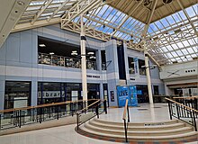 two storey silver clad building set behind an internal glazed square with circular floor feature