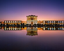 Grâce à son reflet dans un plan d'eau, vue double du palais. Les fenêtres sont éclairées, car la nuit approche.