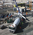 Fully deployed concrete pump, showing outriggers and boom in use while receiving concrete.