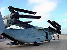 A V-22 with its wing rotated 90 degrees so it runs the length of the fuselage.