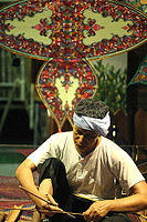 Making a traditional Wau jala budi kite in Malaysia. The bamboo frame is covered with plain paper and then decorated with multiple layers of shaped paper and foil.