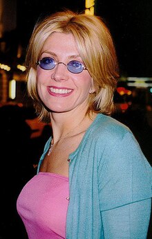 Portrait of Natasha Richardson. She was a young white woman with blonde hair, wearing blue-tinted sunglasses, a pink shirt and light blue cardigan.