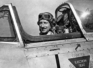 Man in flying cap and goggles sitting in aircraft cockpit