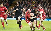 Photographie de cinq joueurs de rugby à XV durant un match.