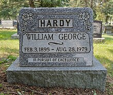 Grey granite marker inscribed with Hardy's full name, birth and death dates, decorated with two flowers, and the iscription "In pursuit of excellence"