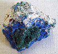 Malachite crystals atop blue azurite, with brown cuprite on the white kaolinite