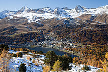 Une ville le long d'un lac avec les montagnes à l'arrière plan.