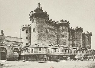 Photographie noir et blanc d'un batiment en pierre avec des tours circulaires.