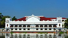 Large white-and-red building on a river