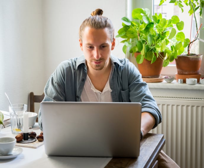 Young man using aptop in the kitchen.