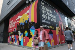 TORONTO, ONTARIO - SEPTEMBER 04: Pedestrians walk past festival signage posted on King Street as preparations are made for the 2024 Toronto Film Festival on September 04, 2024 in Toronto, Ontario. (Photo by Jemal Countess/Getty Images)