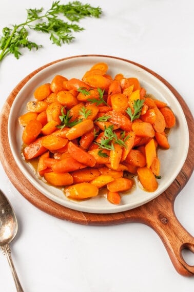 A plate full of honey glazed carrots topped with thyme.