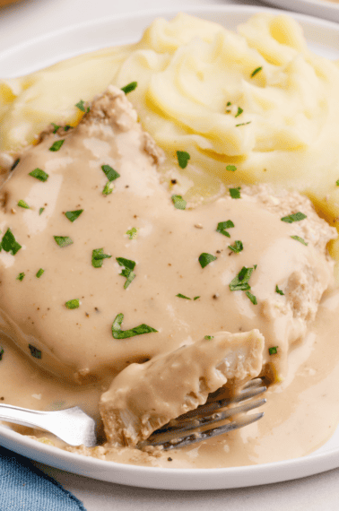 crockpot porkchops on a plate with mashed potatoes and gravy