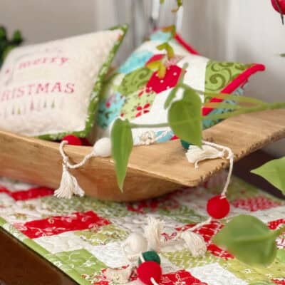 Christmas pillows in wooden bowl on holiday patchwork table runner