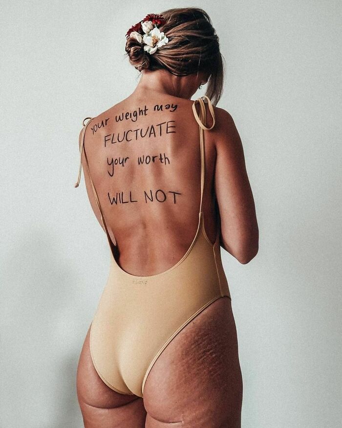 Woman in swimsuit showing empowering body positivity message on her back.