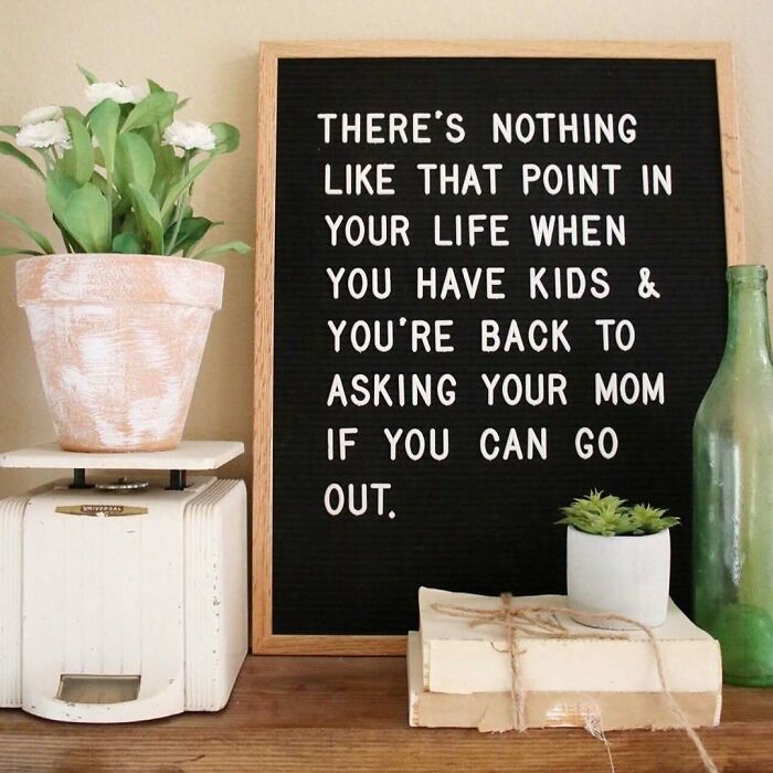 Chalkboard quote about parenthood beside potted plants and vintage decor.