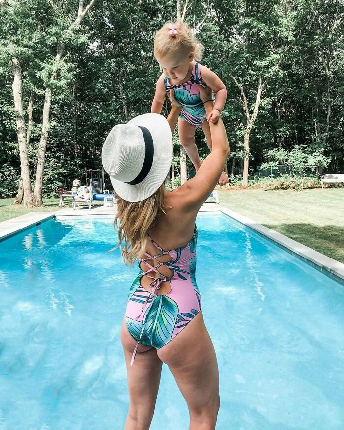 Woman in a swimsuit holding a toddler by a pool, showcasing women in real life moments.