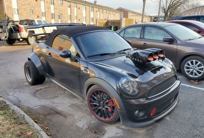 Customized Mini Cooper with large exhaust mods and unusual rear tires, illustrating a car-fails scenario.