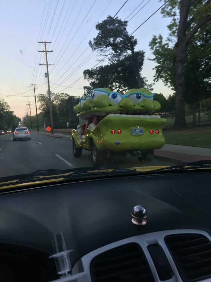 Unusual car shaped like a smiling green creature spotted on the road, showcasing interesting things on a drive.