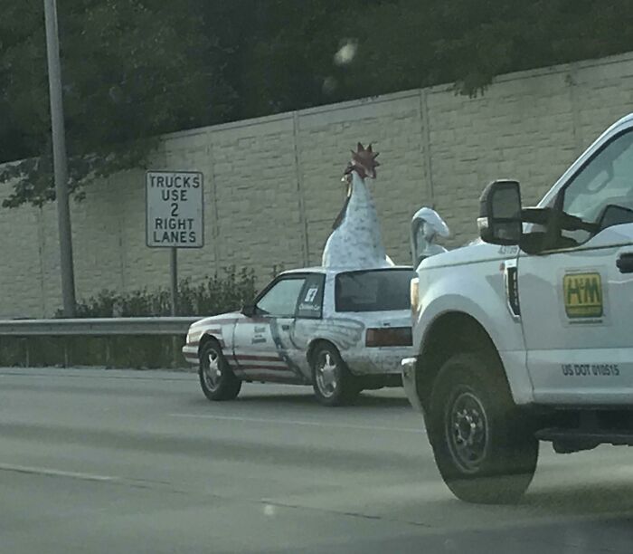 Car shaped like a chicken on the road, creating an unusual sight for drivers in traffic.