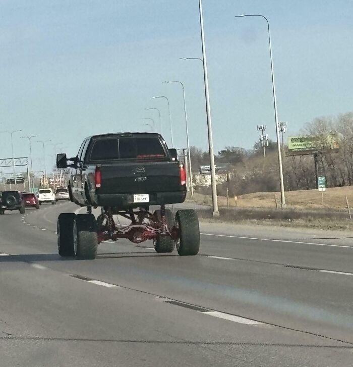 Lifted truck with oversized tires driving on the highway, capturing interesting things on the road.