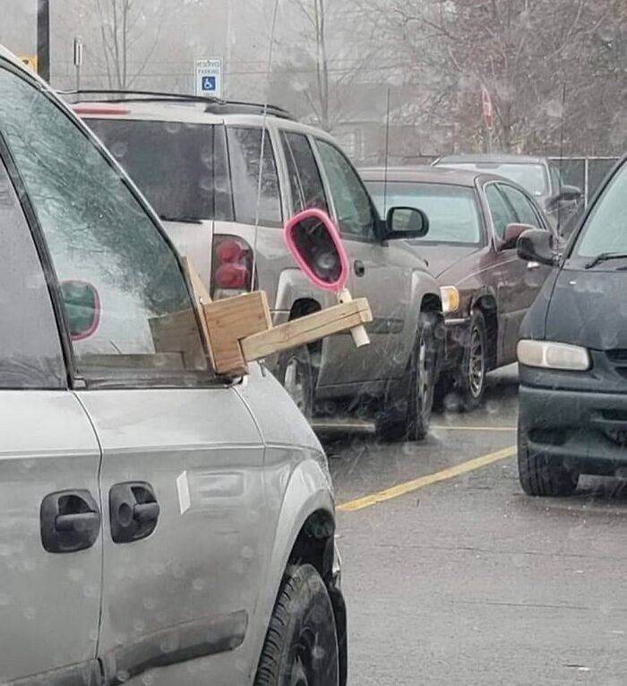 Homemade side mirror with pink plastic frame on a car; creative solution seen on the road.