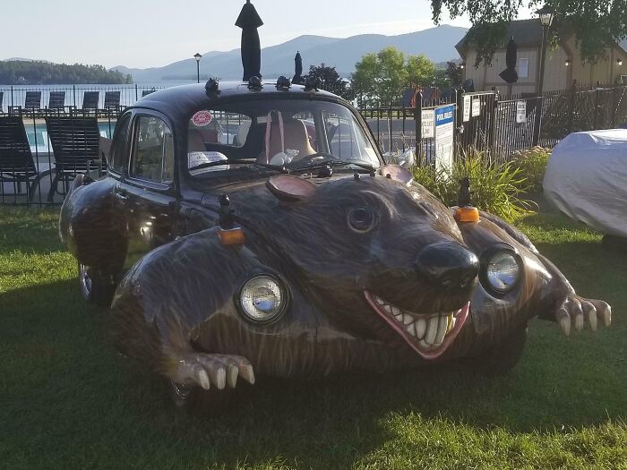 Custom car with a giant rat design on the front, parked on grass near a pool, showcasing a unique car-fail.