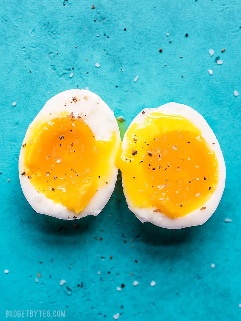 A soft boiled egg cut in half on a blue background