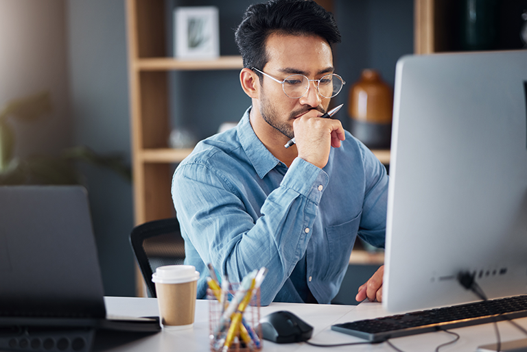 asian male professional working at desktop computer