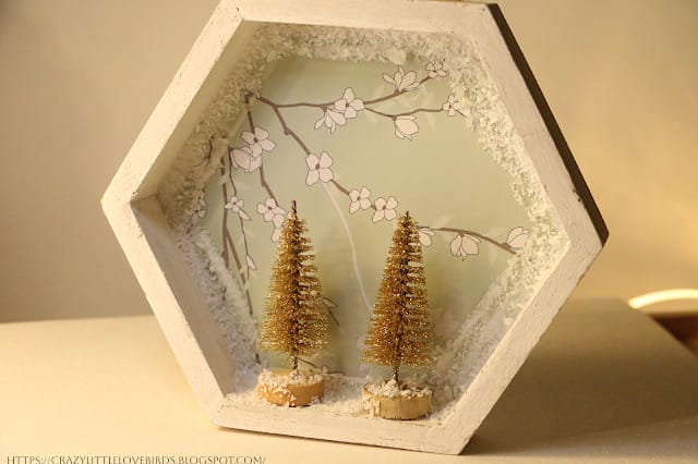 6 sided box with spring flower paper in background and 2 small bottle brush trees in the foreground.