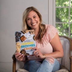 woman in pink shirt holding cookbook