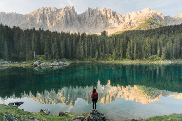 Young Caucasian woman standing and looking at Lago di Carezza in Dolomites